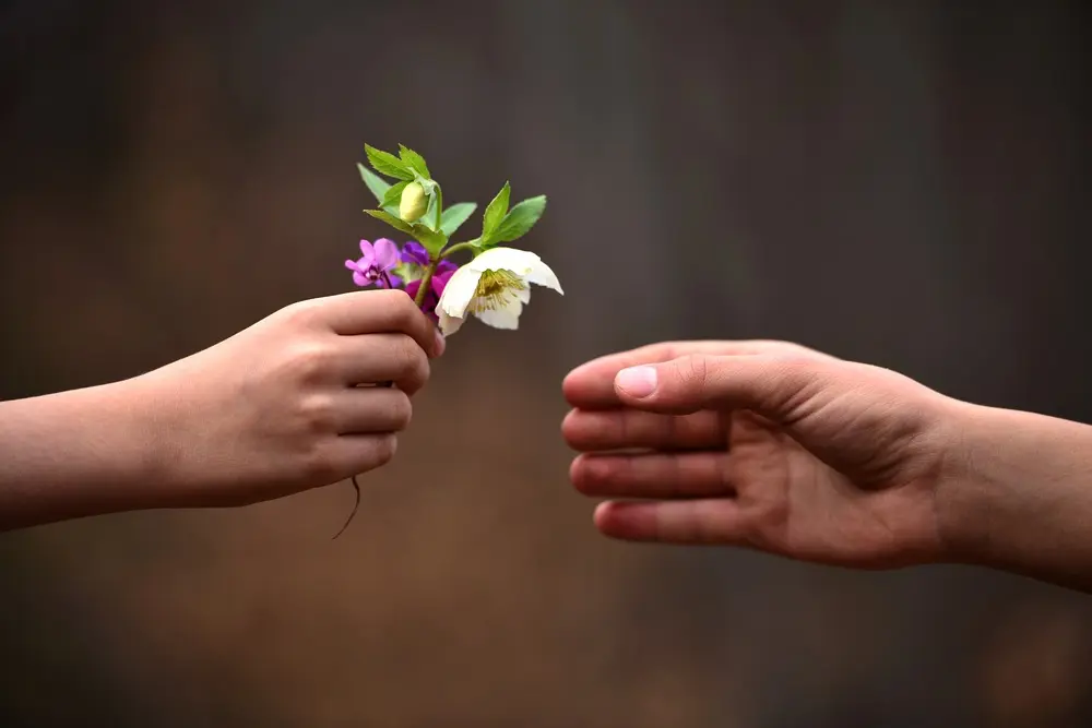 One hand offering a bouquet of flowers to another hand