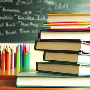 Stack of books with pencils on a school desk and blackboard background